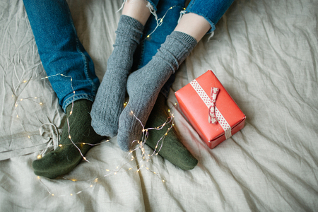 Male crossing legs with woman on the bed with gifts in boxesの写真素材