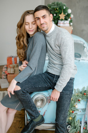 Young caucasian couple sitting on retro car in christmas decorated studioの写真素材