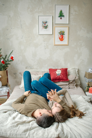 Young caucasian man hugging attractive curly woman on the bedの写真素材