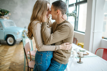 Young caucasian man hugging attractive curvy women in dining roomの写真素材