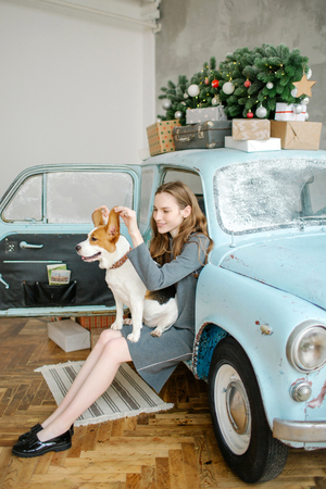Young beautiful caucasian woman with beagle on lap sitting in retro carの写真素材