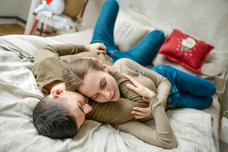 Young caucasian man hugging attractive curly woman on the bedの写真素材