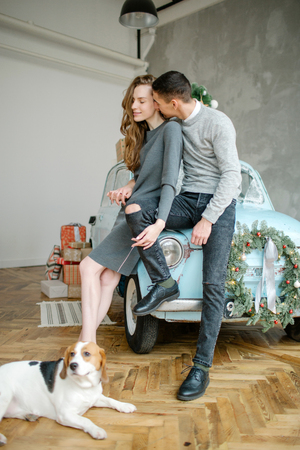 Young couple with beagle and retro car in christmas decorated studioの写真素材