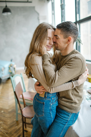 Young caucasian man hugging attractive curvy women in dining roomの写真素材