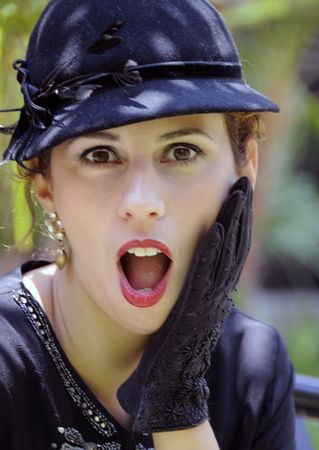 Beautiful woman in sequined black dress with black hat, in front of tropical foliageの写真素材
