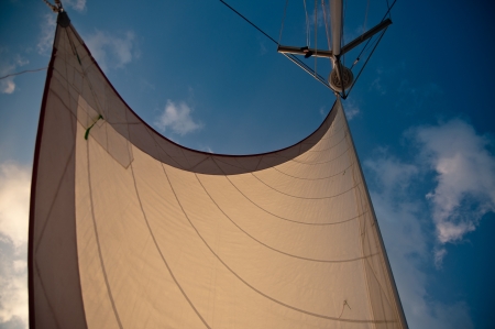 White sail set against blue sky and white clouds