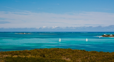 Two small white sailboats in the crystal clear blue and turqoise waters of the bahamasの写真素材