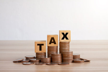 Wooden blocks with the word TAX on stacked coins. concept of income tax.の写真素材