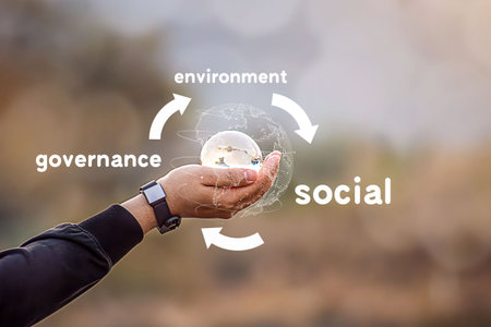 Hand of human holding green earth ESG icon with sunlight on a green background. for Environment Social and Governance, World sustainable environment concept.の写真素材