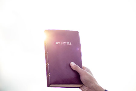 Person holding a Bible in the air