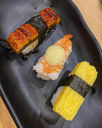 Black ceramic tray with variety of sushi salmon, seafood roll and grilled beef appetizing meal in japanese restaurantの写真素材