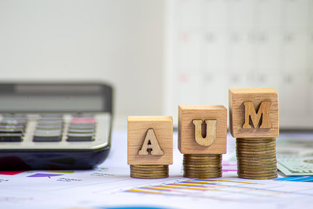Assets under management (AUM) is the total market value of the investments that a person or entity manages on behalf of clients.The word is written on money and gold backgroundの写真素材
