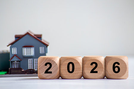 Wooden blocks displaying the year 2026 next to a model house.