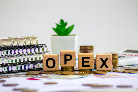 OPEX written on a wooden cube on the keyboard with office tools
