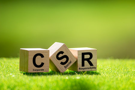 CSR (coporate social responsibility). words CSR on a woodblock and green world on a green background...