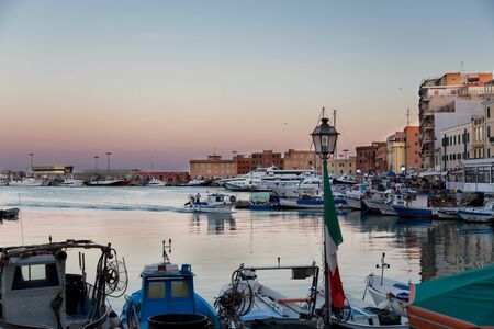 Anzio, Lazio region, Italy - August 27, 2018: Small picturesque city port at sunset. Fishing boats, small yachts on beautiful evening sky background. Lovely Italian city on the sea cost.のeditorial素材