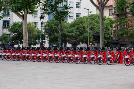 Barcelona, Spain - July 9, 2019: Bright red bicycles available for rent parked in a row at Passeig...