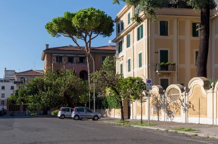Rome, Italy - September 29, 2019: Lovely quiet street on Aventine hill. Parked cars, beautiful Italian stone pines near houses on blue sky background. No people.のeditorial素材