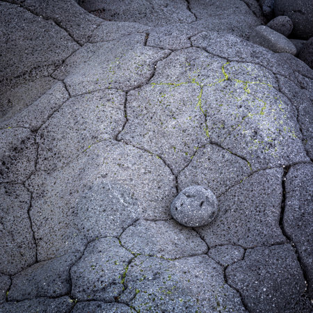 A round lava stone perfectly fitted into a small cavity in big, grey vulcanic rock, Hvaleyri beach, Icelandの写真素材
