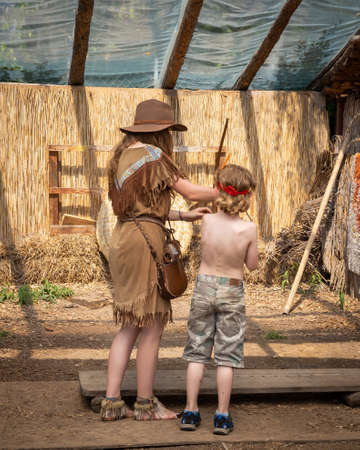Wroclaw, Poland - June 21, 2021: A boy child learning a native Indian bow shooting with a lady kids entertainer in a western costume.のeditorial素材