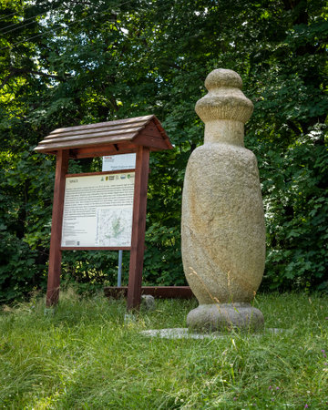 SOBOTKA, POLAND - July 6, 2021: A prehistoric stone monk statue and information board on a tourist route to Sleza peak.
Green grass, forest in background.のeditorial素材