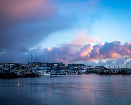 HAFNARFJORDUR, ICELAND - July 16, 2021:
Sunset in Hafnarfjordur fishing harbour. Pink clouds in the sky. Sailboats, small fishing boats and port buildings.のeditorial素材