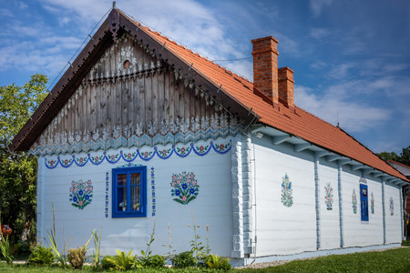 ZALIPIE, POLAND - August 1, 2021:
A traditional, white wooden cottage, with walls painted in colorful floral pattern.のeditorial素材