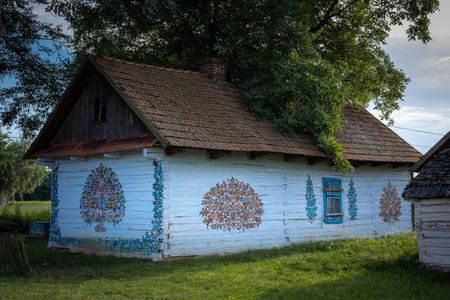 ZALIPIE, POLAND - August 1, 2021:
A traditional, white wooden cottage, with walls painted in colorful floral pattern.のeditorial素材