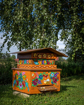 ZALIPIE, POLAND - August 1, 2021:
An orange wooden beehive in the garden, painted in floral pattern. Sunny, summer day.のeditorial素材