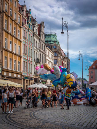 Wroclaw, Poland - August 7, 2021:  People walking in old Town market square on sunny, summer day. Colorful balloons. Beautiful residential houses.のeditorial素材