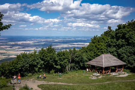 SLEZA, POLAND - August 07, 2021: A tourist wooden hut surrounded with trees, on the top of Sleza mountain, Sudetes Foreland. Sunny, summer day. Blue, partially clouded sky.のeditorial素材