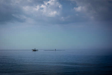 A motorboat pulling water skier on the calm and still sea. Zero Beaufort. 
Background with copyspace.の写真素材