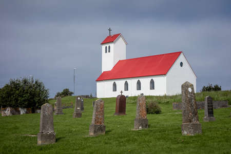 Hafnarfjordur, Iceland - July 17, 2021:
Traditional icelandic church with red rooftop, Old vertical stone tombs on the cemetery in front of the church.のeditorial素材