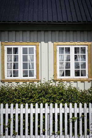 Hafnarfjordur, Iceland - July 17, 2021:
A closeup of a traditional icelandic cottage in Hafnarfjordur museum. White Wall, two windows and a white wooden fence.のeditorial素材