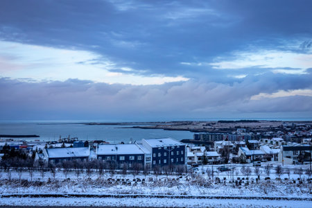 Hafnarfjordur, Iceland - November 24, 2021: A city panorama on a dark, snowy winter day. Residential buildings on the seaside. Gray, cloudy sky.のeditorial素材