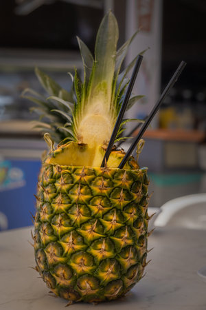 A pinacolada coctail in fresh pineapple fruit on the beachbar table.