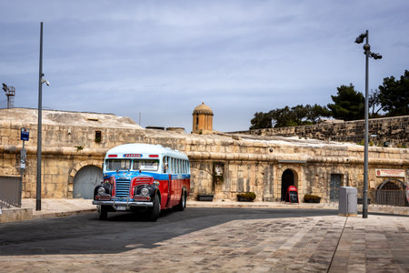 Valletta, Malta - April 18, 2023: A vintage, red, white and blue Maltese bus parked in downtown street.のeditorial素材