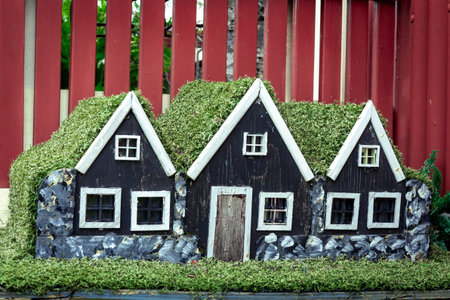 Three small black wooden elf houses with green moss roof, typical for Iceland.