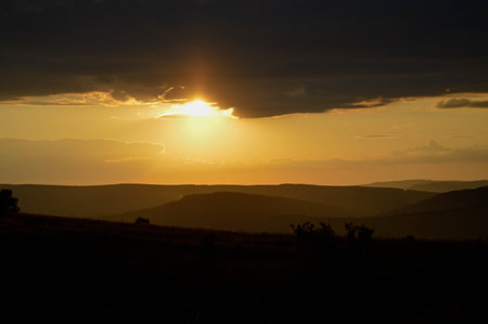 Sunset in the wild, mountain twilight orange light, landscape, clouds and the sky.の写真素材