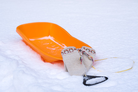 Winter fun, wooly gloves and orange sledの写真素材