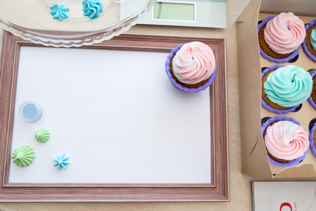 wooden frame with white sheet around meringue and cupcake with multi-colored cream, kitchen scale, magazineの写真素材