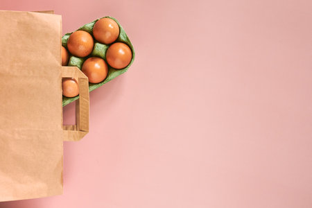 Kraft bag with chicken eggs in tray on beige background, shopping concept, space for text.の写真素材
