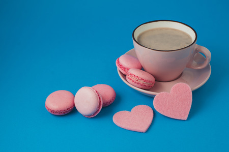 pink macaroons and hearts with cup of cocoa on blue background. valentine's dayの写真素材