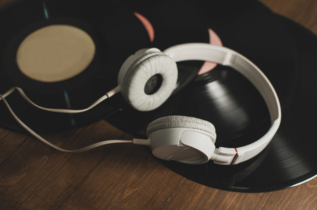 vinyl records on a wooden background and white headphonesの写真素材