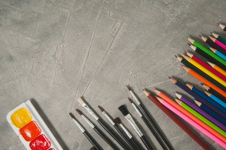 Drawing accessories - pencils, paints and brushes on a gray backgroundの写真素材