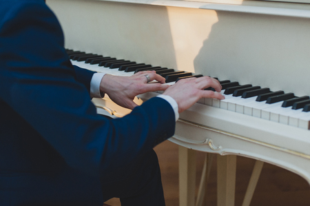 Pianist is playing on a white piano. Musical event, concert of classical musicの写真素材
