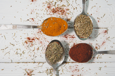 Spoons with different spice - rosemary, turmeric, oregano, paprika.の写真素材