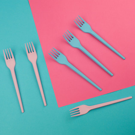 Pink and blue painted forks on the same colors background. Abstract artistic concept. Flat lay.