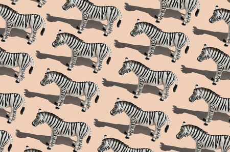 Pattern made with zebra toy on light beige background. Trendy picture with hard shadows.の写真素材