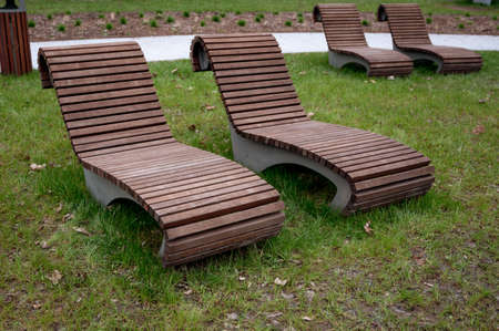 Bench in the park, wooden brown lounge chairs on the recreation areaの写真素材